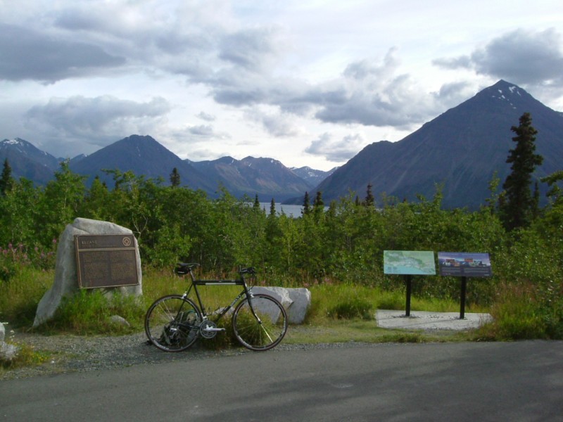 Right side view of a Surly bike, parked in front of an area with park signs, with trees and mountains in the background