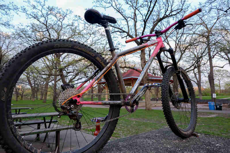 Surly Instigator bike - pink and gray - right side view - city park setting with a shelter in the background
