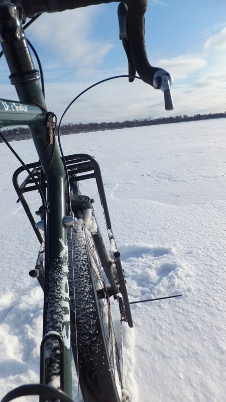 Rear, right side view of the front end, of a green Surly Disc Trucker bike, standing on a snow covered frozen lake