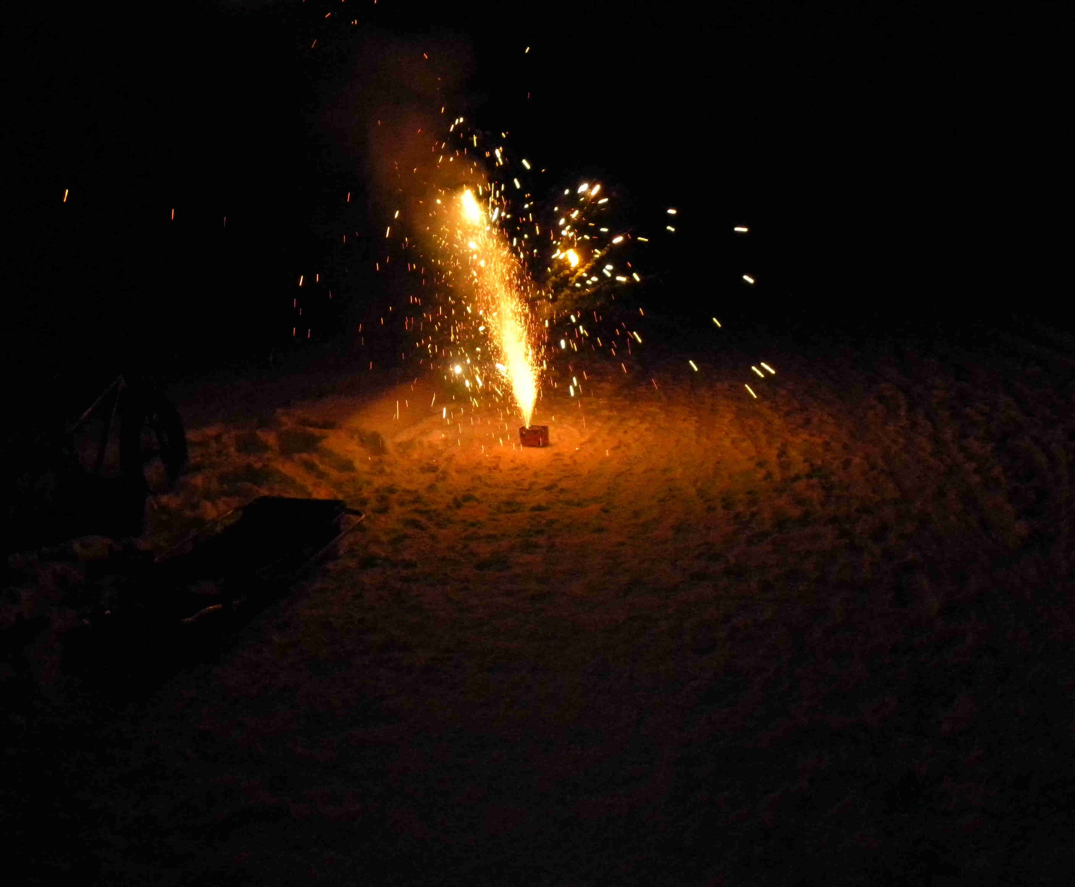 Nighttime view of fireworks showering sparks upward from a snow covered ground