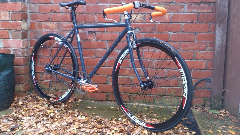 Right side view of a Surly bike, leaning against an exterior brick wall