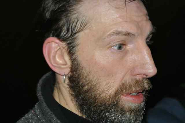 Right side head shot of a person with a beard and eyes wide open, at nighttime
