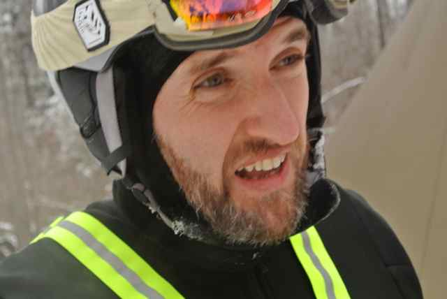 Headshot of a person with a beard, wearing a helmet with goggles on top