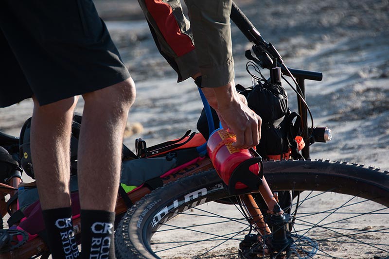Mountain bike laying on ground as person removes water bottle from fork attachment