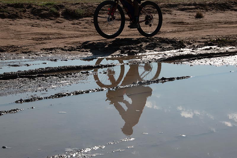 Large mud puddle on gravel road, mountain biker rides around