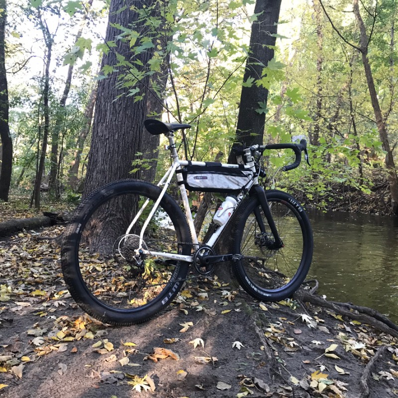 Right side view of a Surly Midnight Special bike leaning on a tree next to a stream in the woods