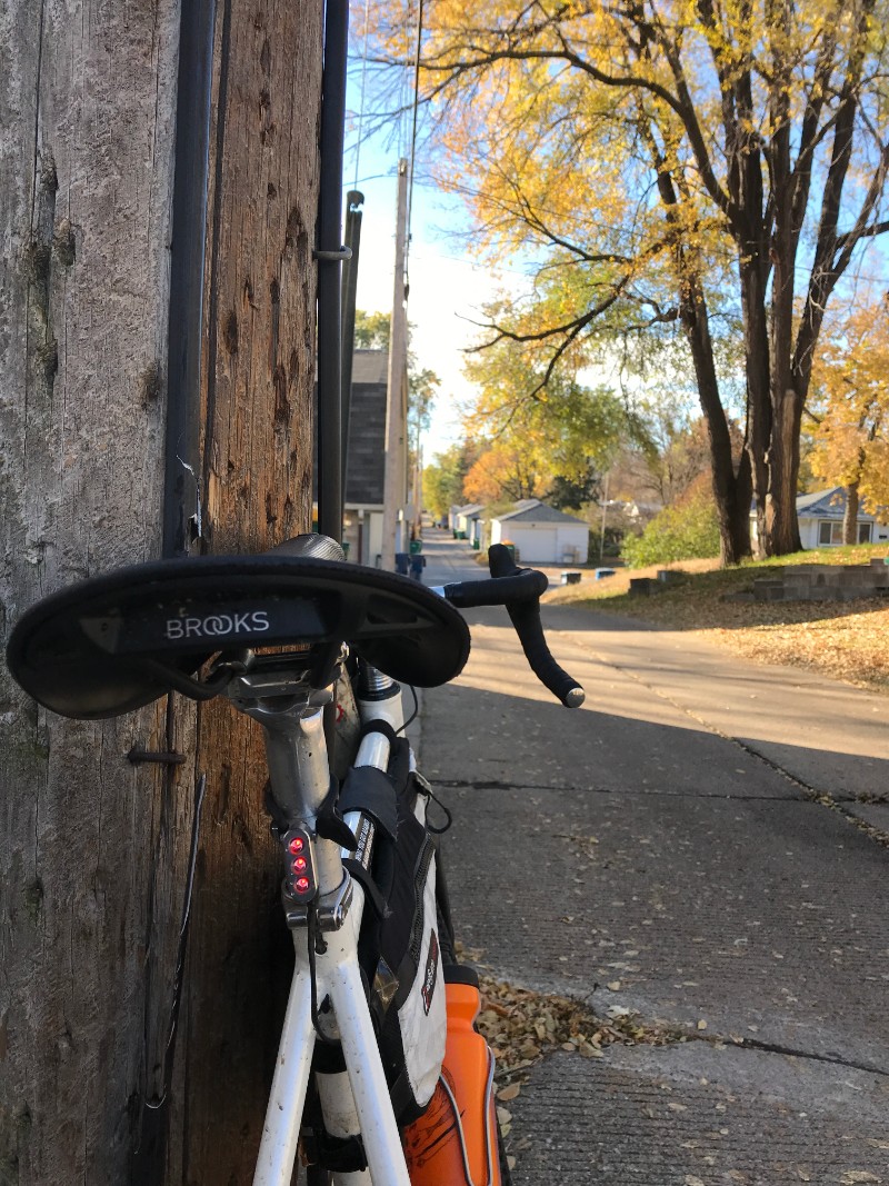 Rear view of a Surly Midnight Special bike facing up a paved alley while leaning on a telephone pole