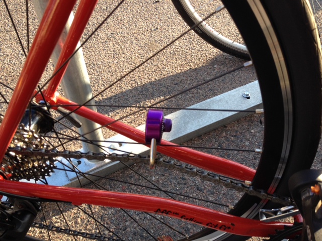 Cropped right side view of a red Surly Disc Trucker bike, showing a purple lock around the chain and chainstay