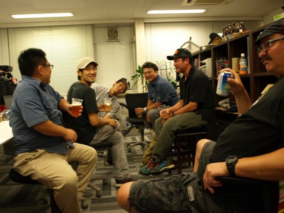 A group of people, sitting in an office room, drinking beer