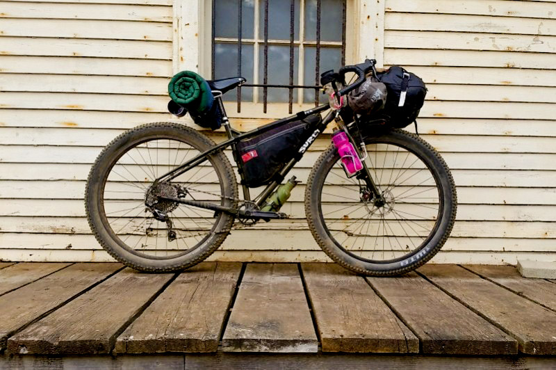 Right profile of a Surly ECR bike, parked on a wood deck, in front of a white wall of a house