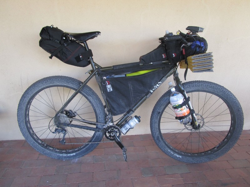 Right side view of a Surly ECR bike with gear packs, parked against a white wall