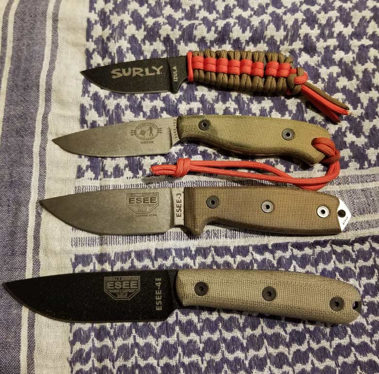 Four fixed blade knives with Surly and ESEE logos shown smallest to largest, lying on a woven blue and white blanket