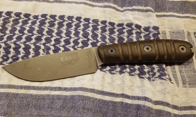 ESEE Knife with gray blade and brown handles laying on a blue and white woven towel