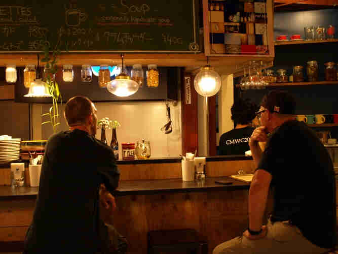 Rear view of 2 people, sitting at a counter in a Japanese cafe
