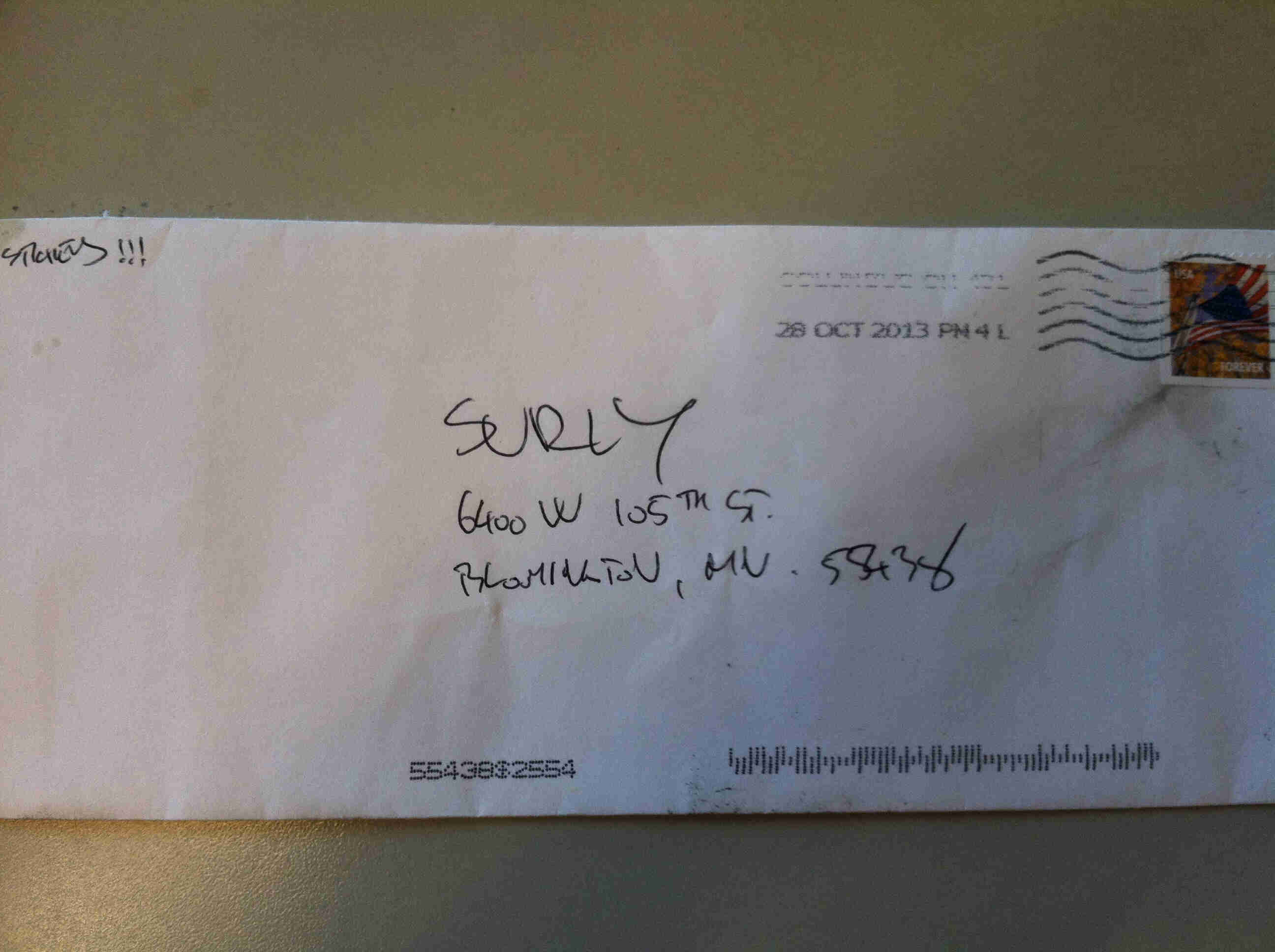 Horizontal view of outside of a white envelope, addressed to Surly, laying on a table top