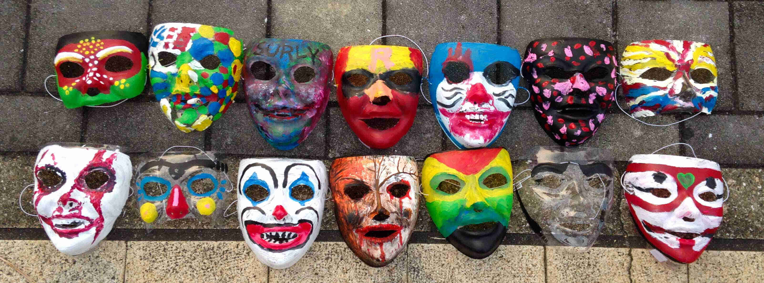 Downward view of masks, lined up on a brick sidewalk