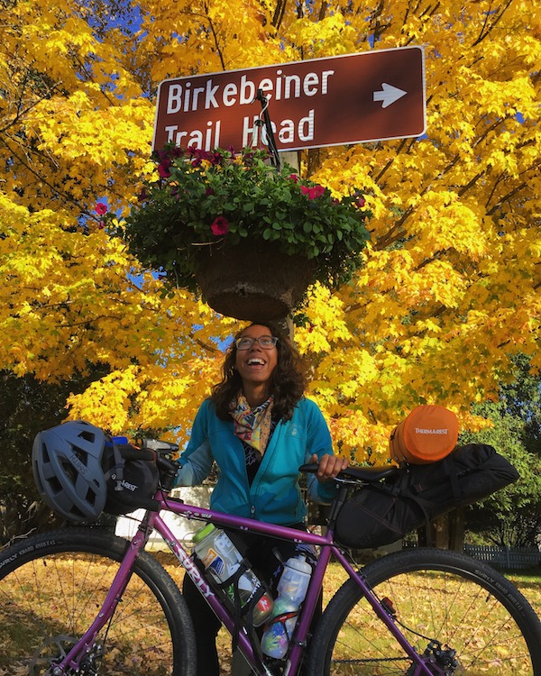 Left profile view of a Surly Straggler bike with cyclist standing behind with a yellow leafed tree in the background