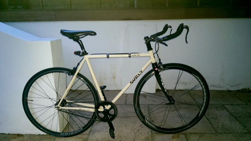 Right side view of a white Surly bike, parked on a stone block floor