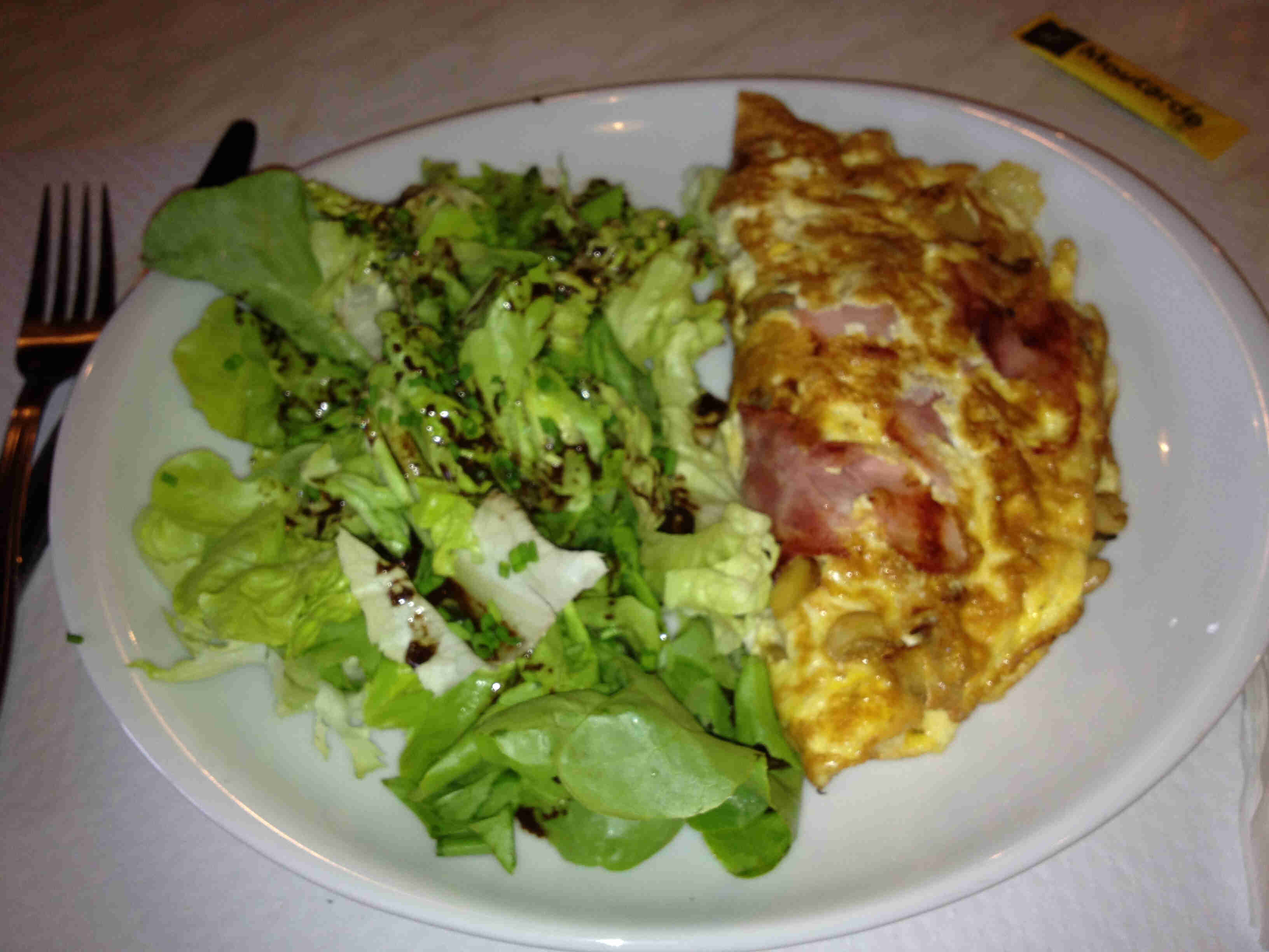 An omelet and green leafy vegetables on a white plate