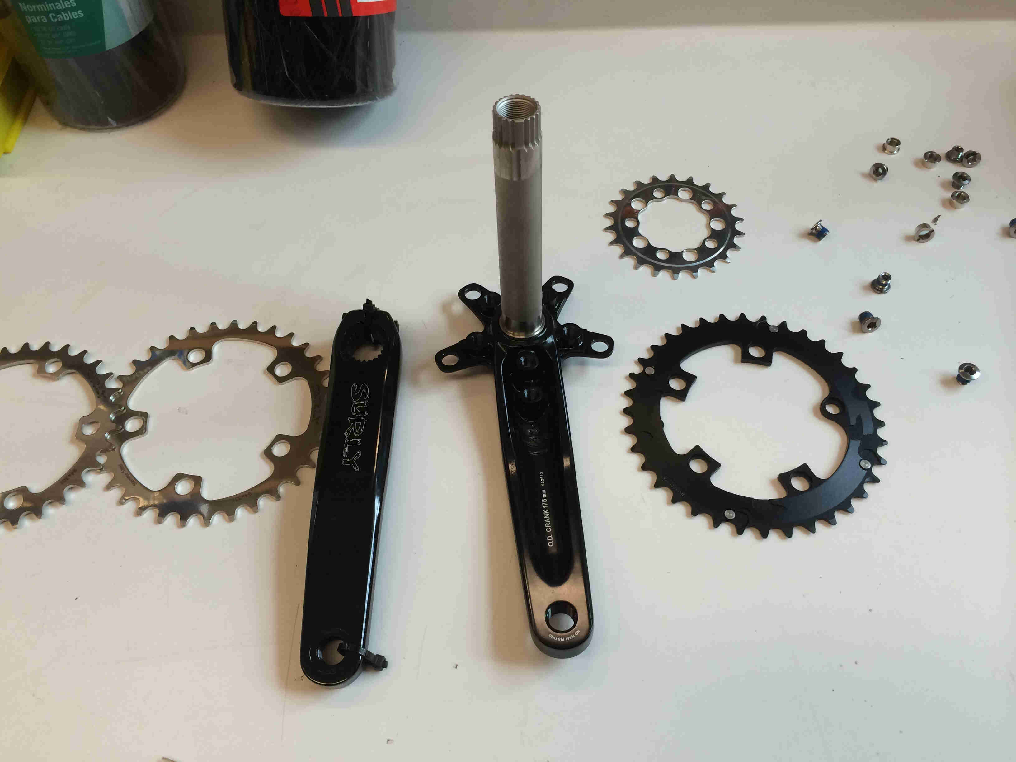 Downward view of Surly Bikes O.D Crankset and chainrings, fully disassembled, on a table