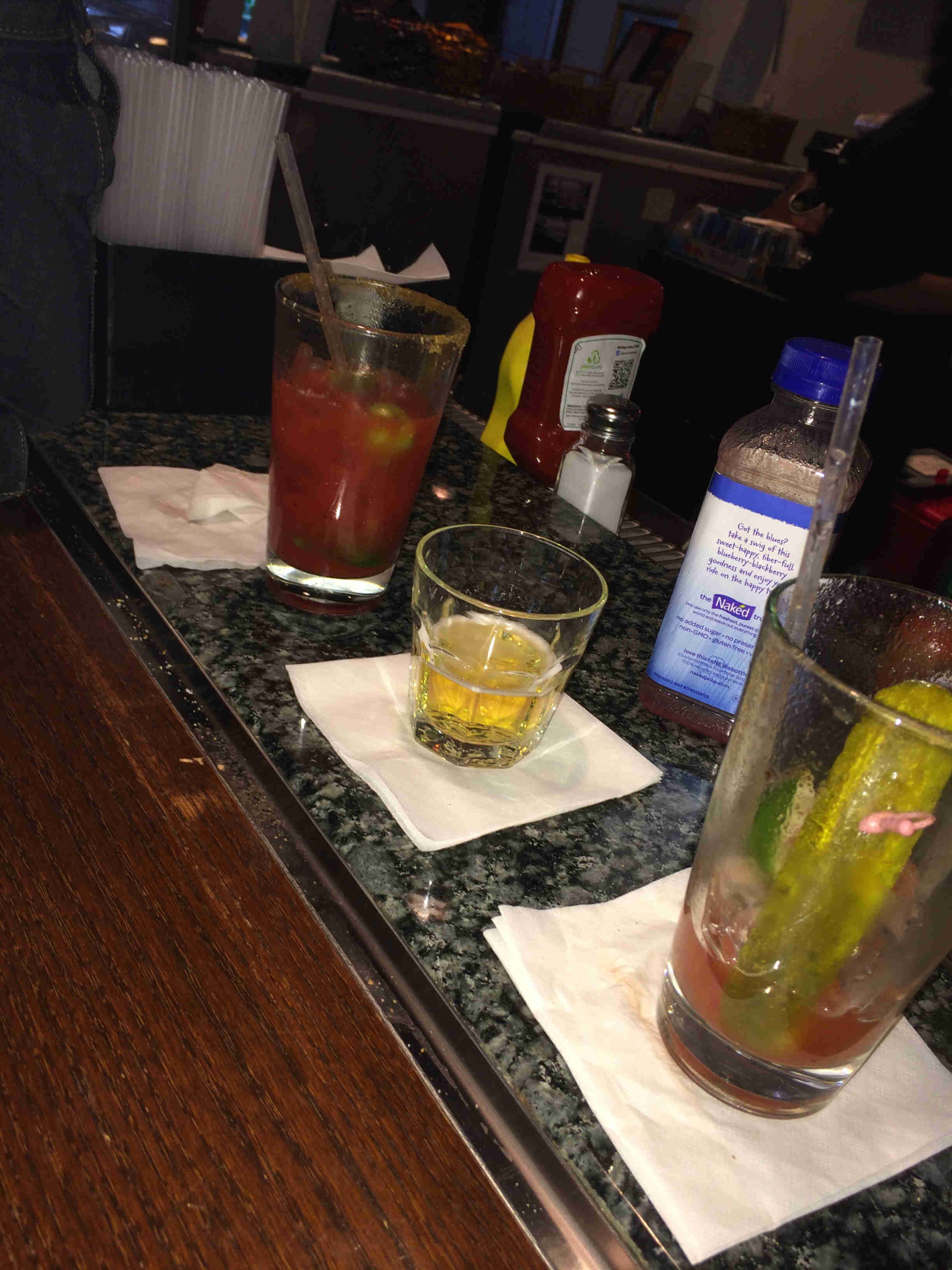 Glasses of mixed drinks, sitting on a granite bar top