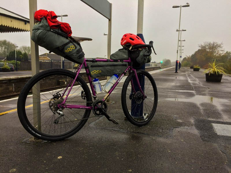 Right side view of a purple Surly bike on a platform of a train rail station