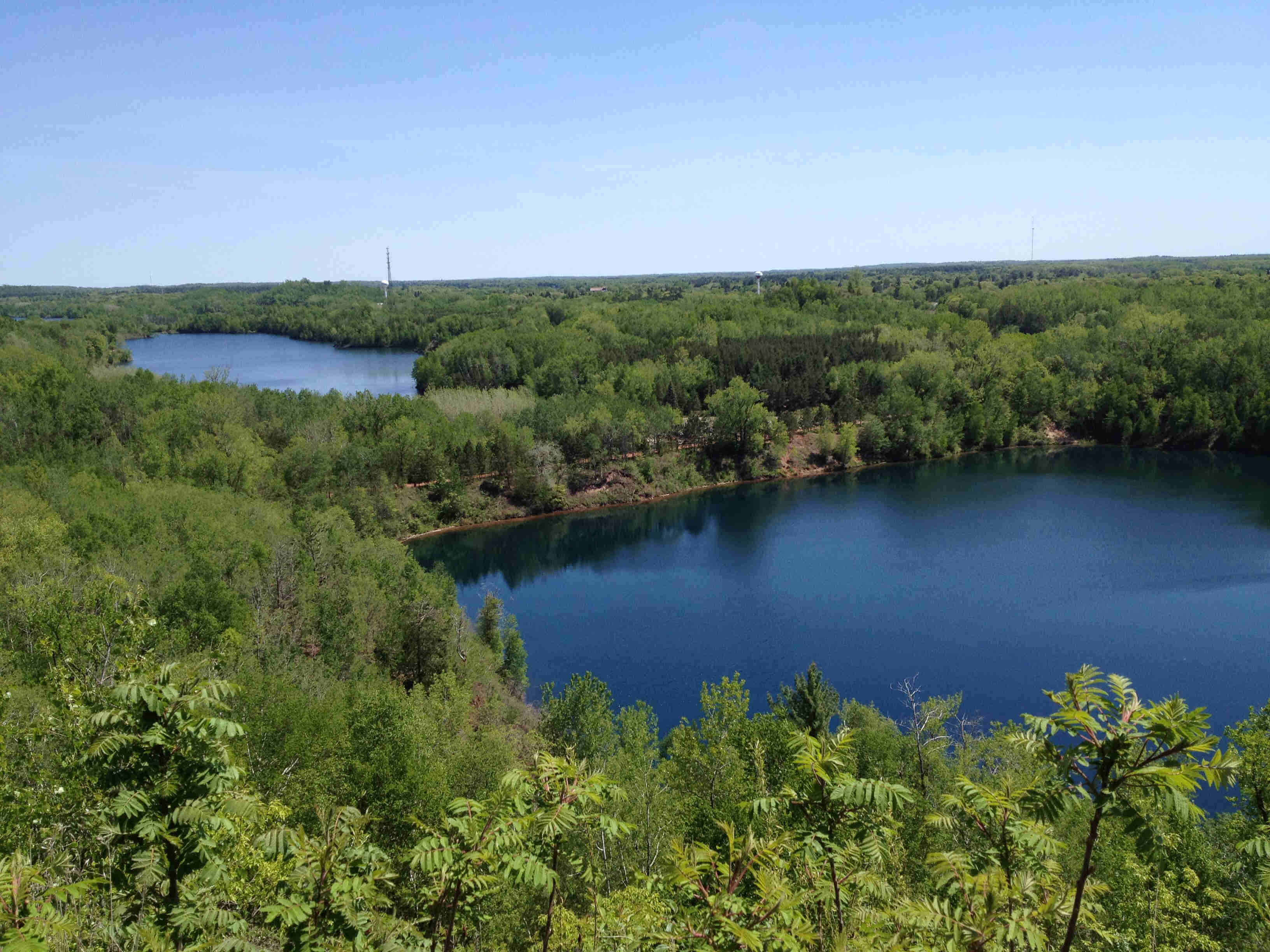 Hilltop view of 2 lakes, completely surrounded by a thick, green forest