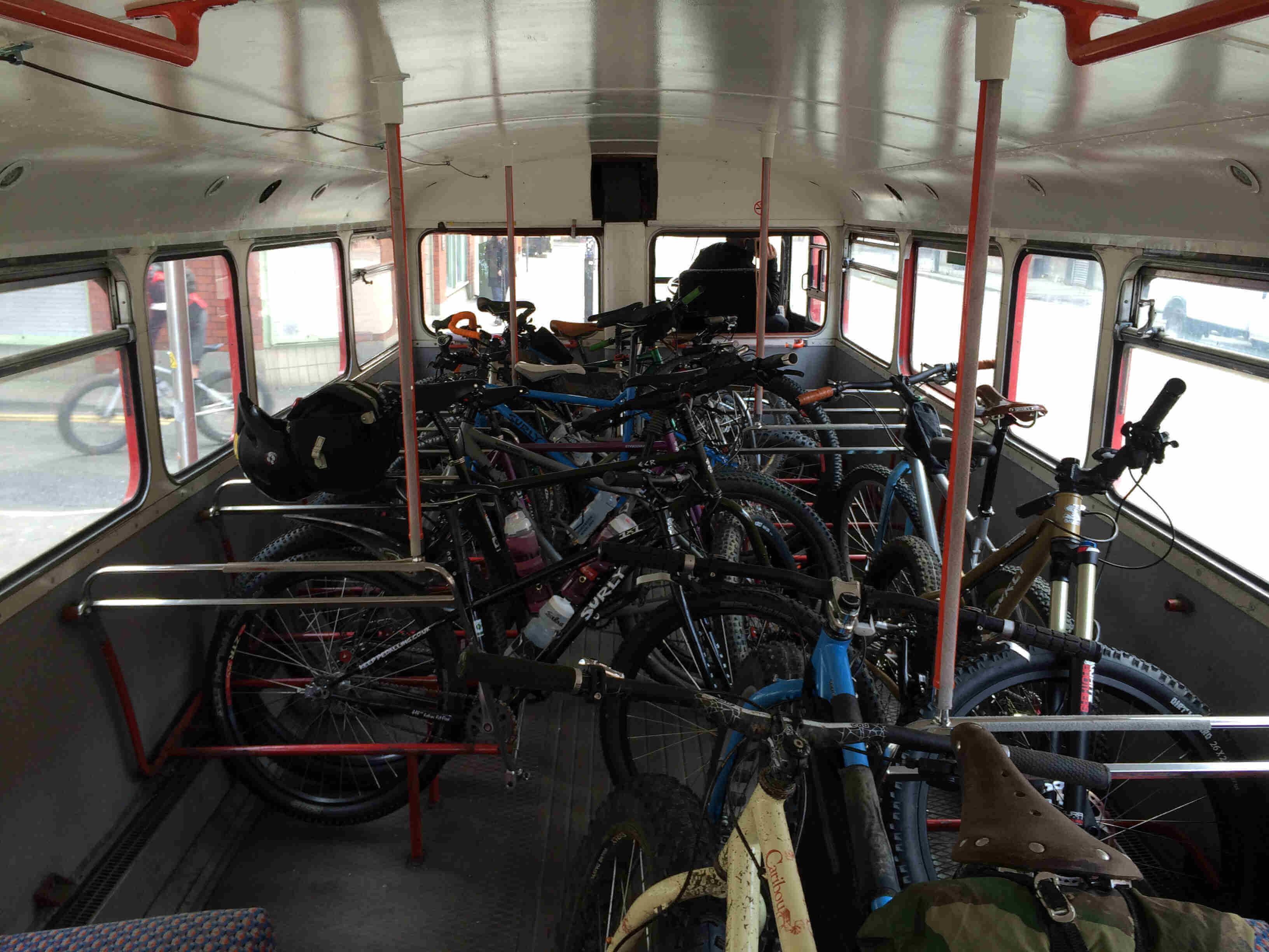 A view from the inside of a bus with Surly bikes parked sideways and leaning against each other