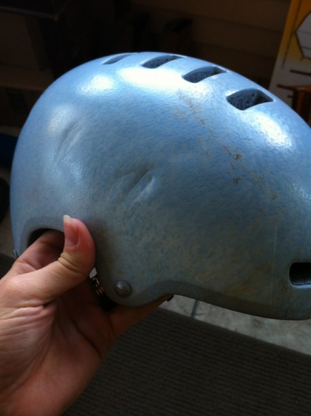 A person's holding a dented, blue bike helmet