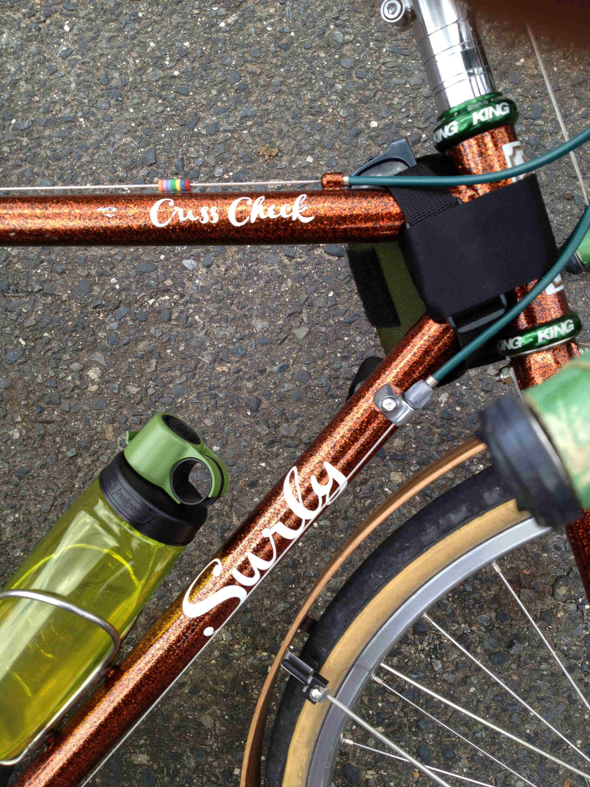 Downward, right side, front end view of a copper Surly Cross Check bike, laying on pavement