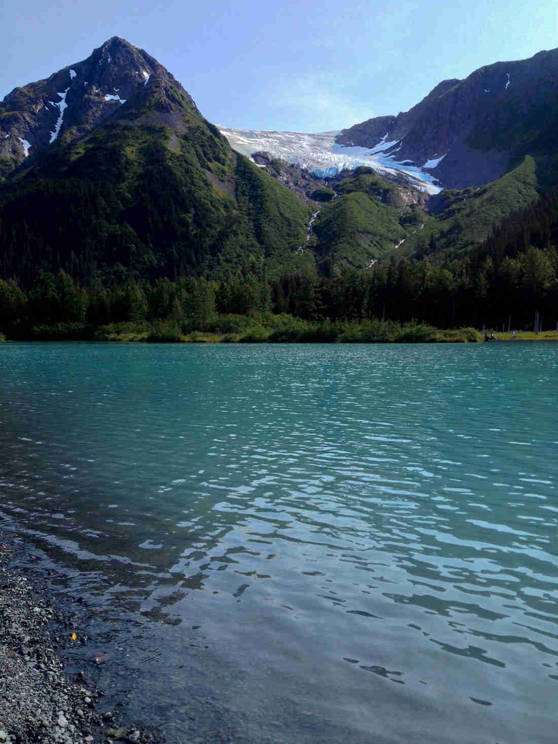 A turquoise, bluish lake, with a glacier on a mountain behind it