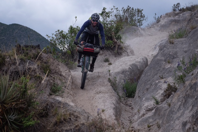 Front view of a cyclist riding a Surly Krampus bike down a rocky, mountain trail
