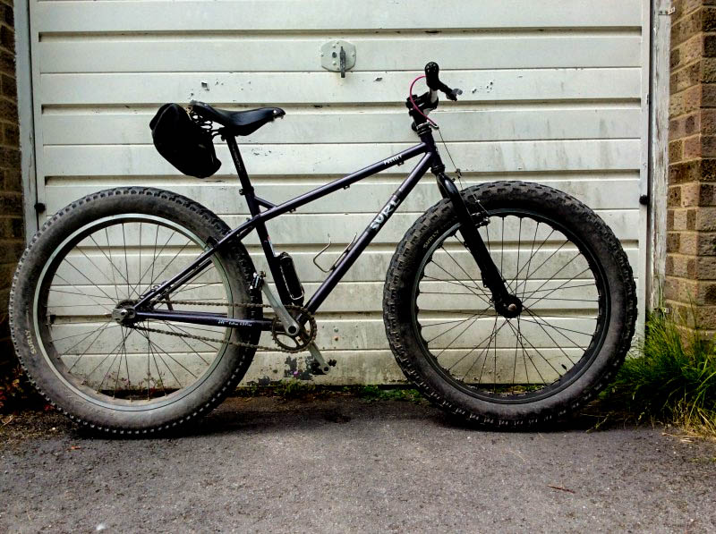 Right profile of a Surly fat bike with a white garage door behind it