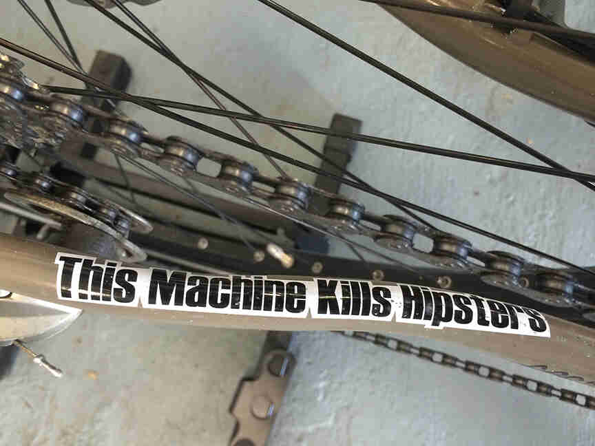 Downward, close up view from the chainstay of a Surly Ogre bike, with a sticker showing, This Machine Kills Hipsters
