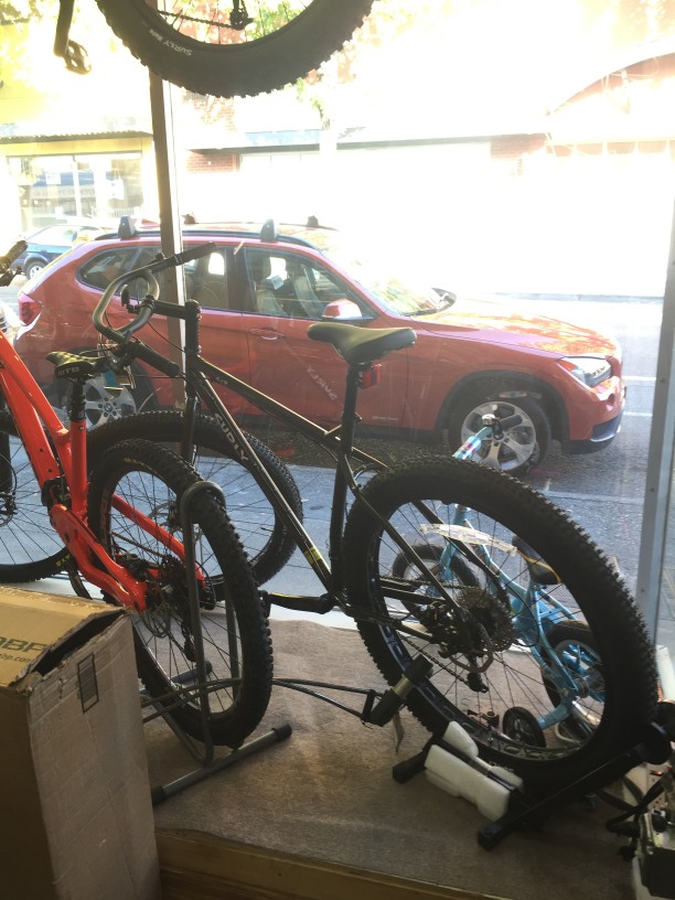Rear, left side view of a black Surly fat bike, from the inside of a storefront window