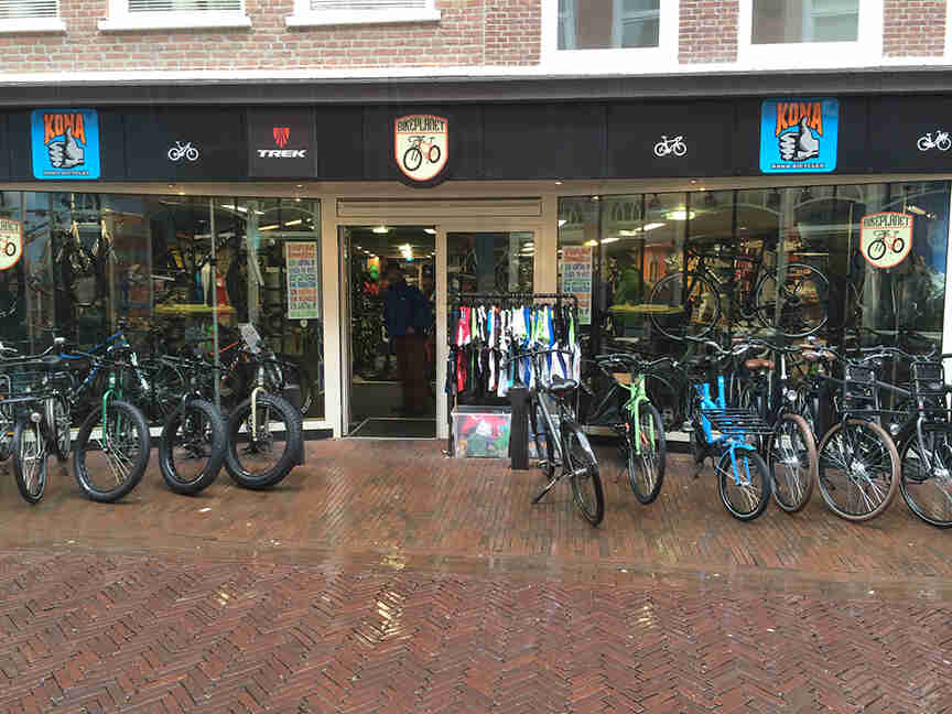 Front, outdoors view of a bike shop, with bikes lined up side by side, in front of it