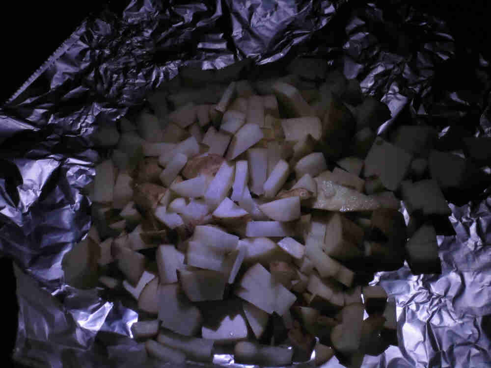 A sheet of tin foil with cut up potatoes inside