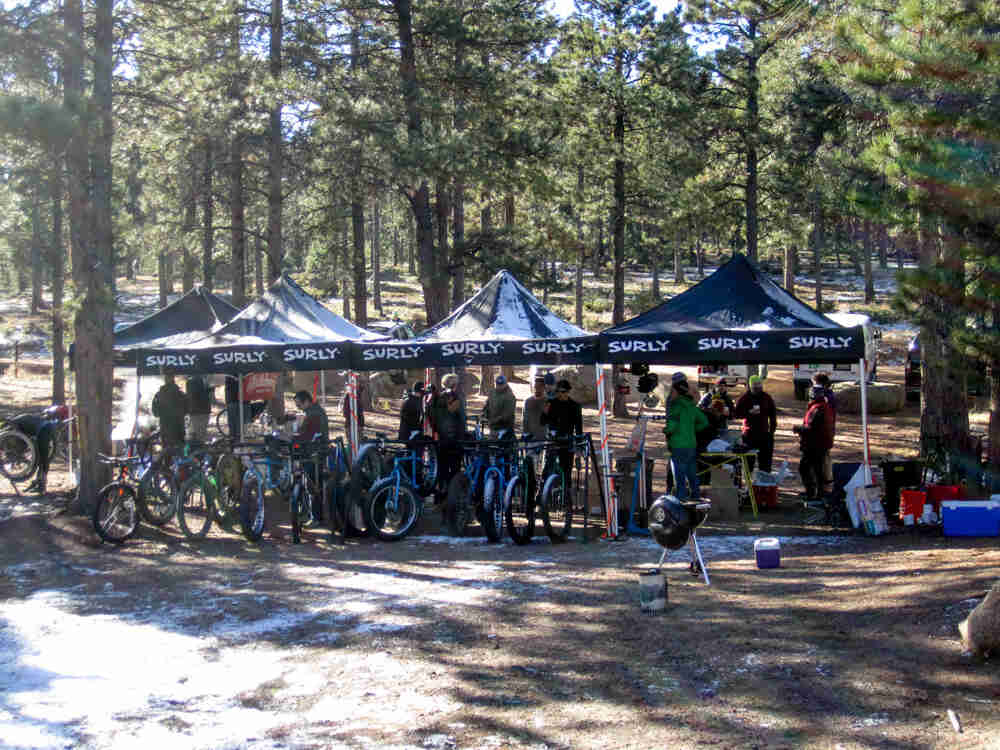 People and bikes underneath Surly canopies, on a clearing in the forest