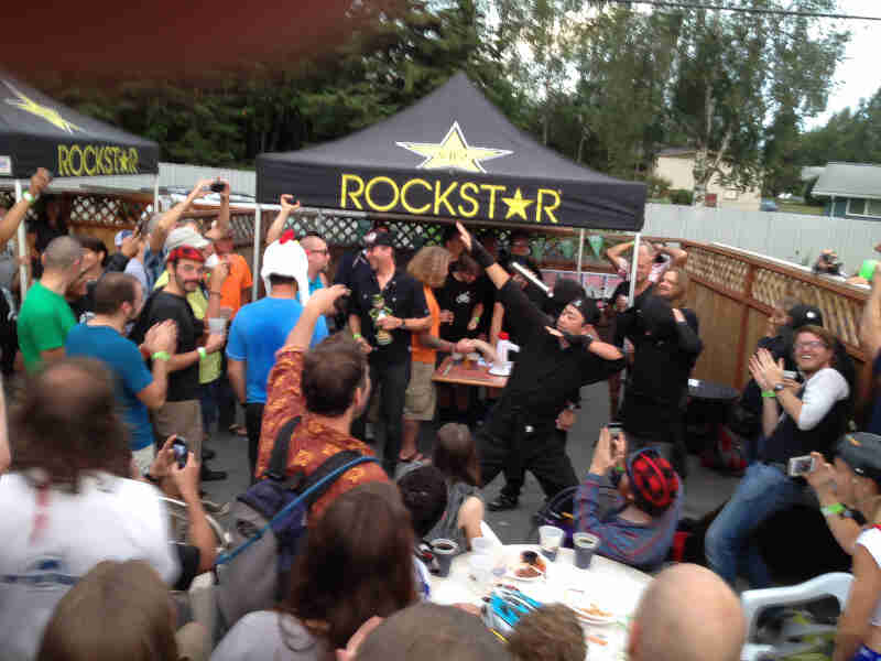 A group of people, gathered on an outdoor patio with two Rockstar Beverage canopies on it