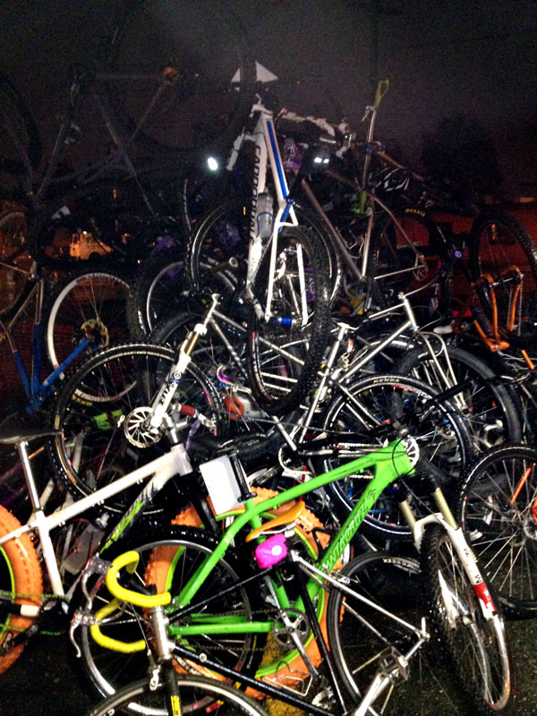 A large number of bikes stacked together to form a bike tower, at nighttime