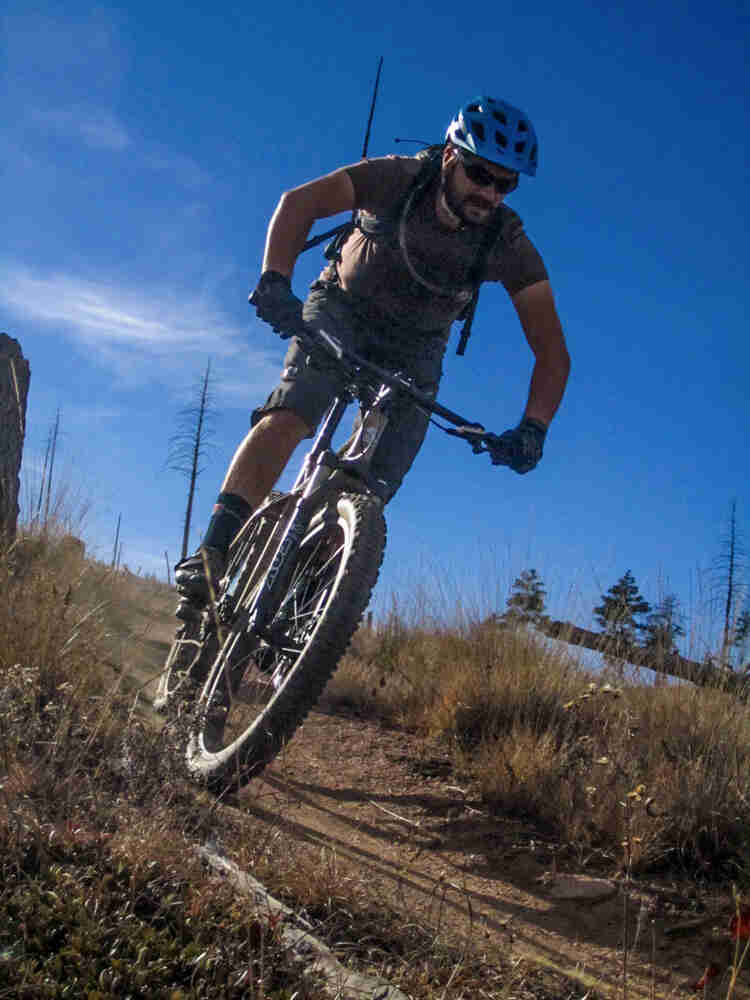Front view of a cyclist riding a Surly Instigator bike down a dirt trail on a grassy hill