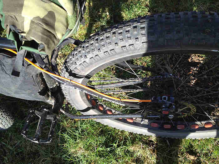 Downward, left side, rear end view of a black Surly Pugsley fat bike, parked on green grass