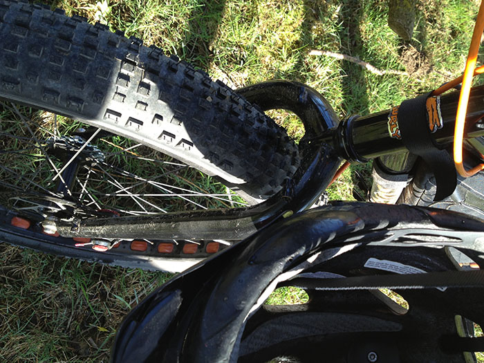 Downward, front end view of a black Surly Pugsley fat bike, parked on a grass area