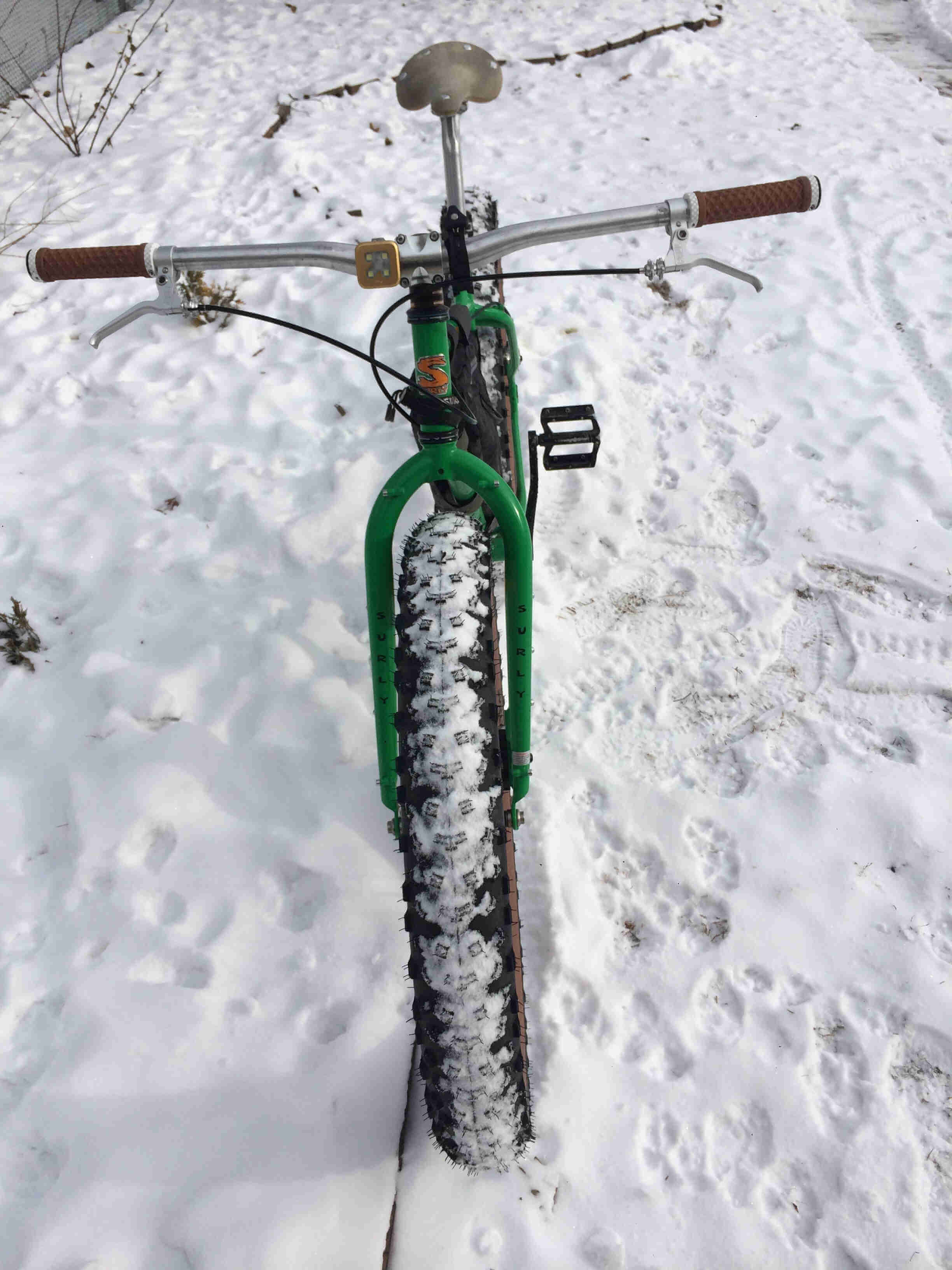 Front view of a green Surly Pugsley fat bike with offset forks, parked on snowy ground