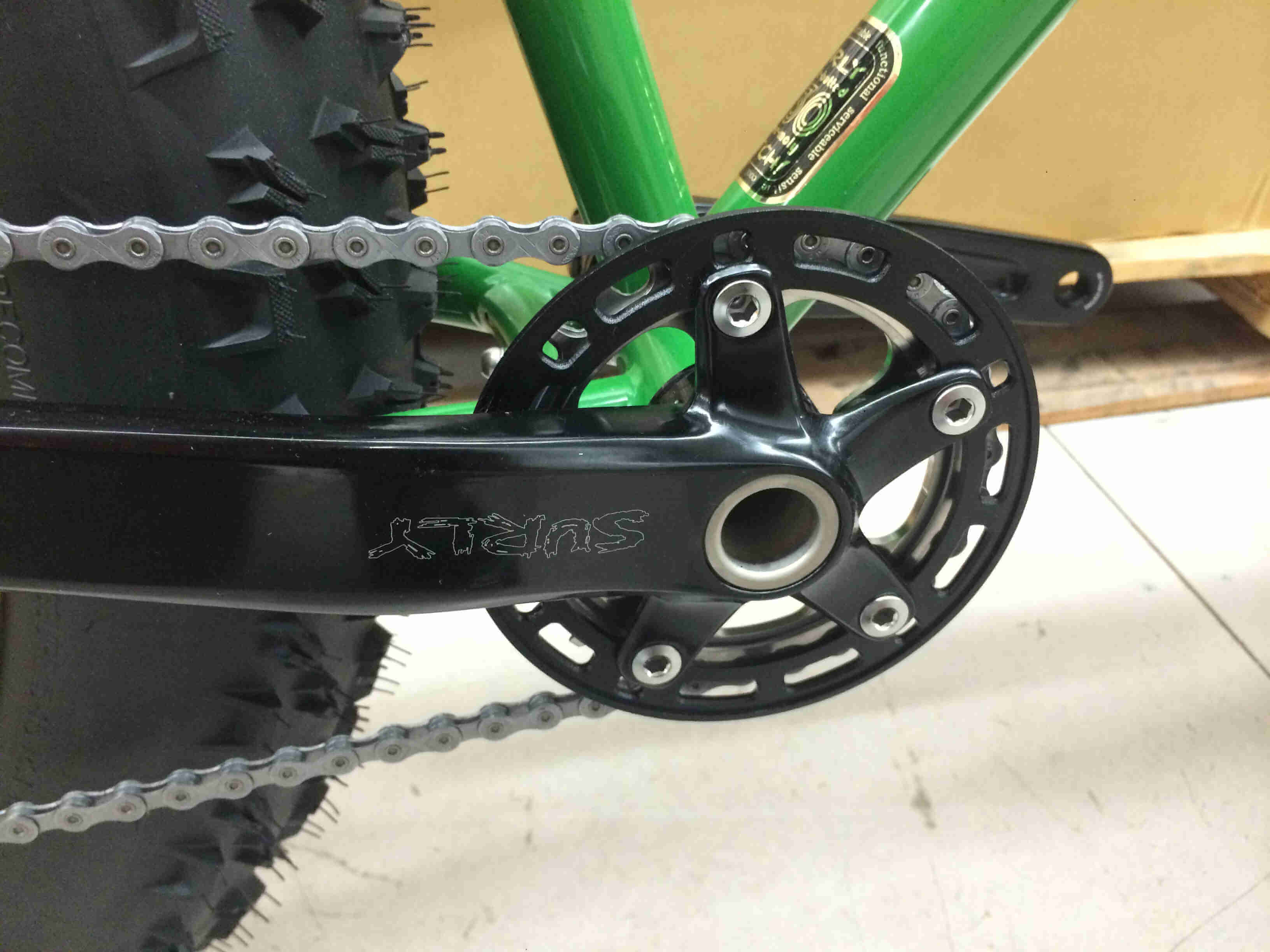 Close up, right side view of the crank and chainring of a green Surly Moonlander bike