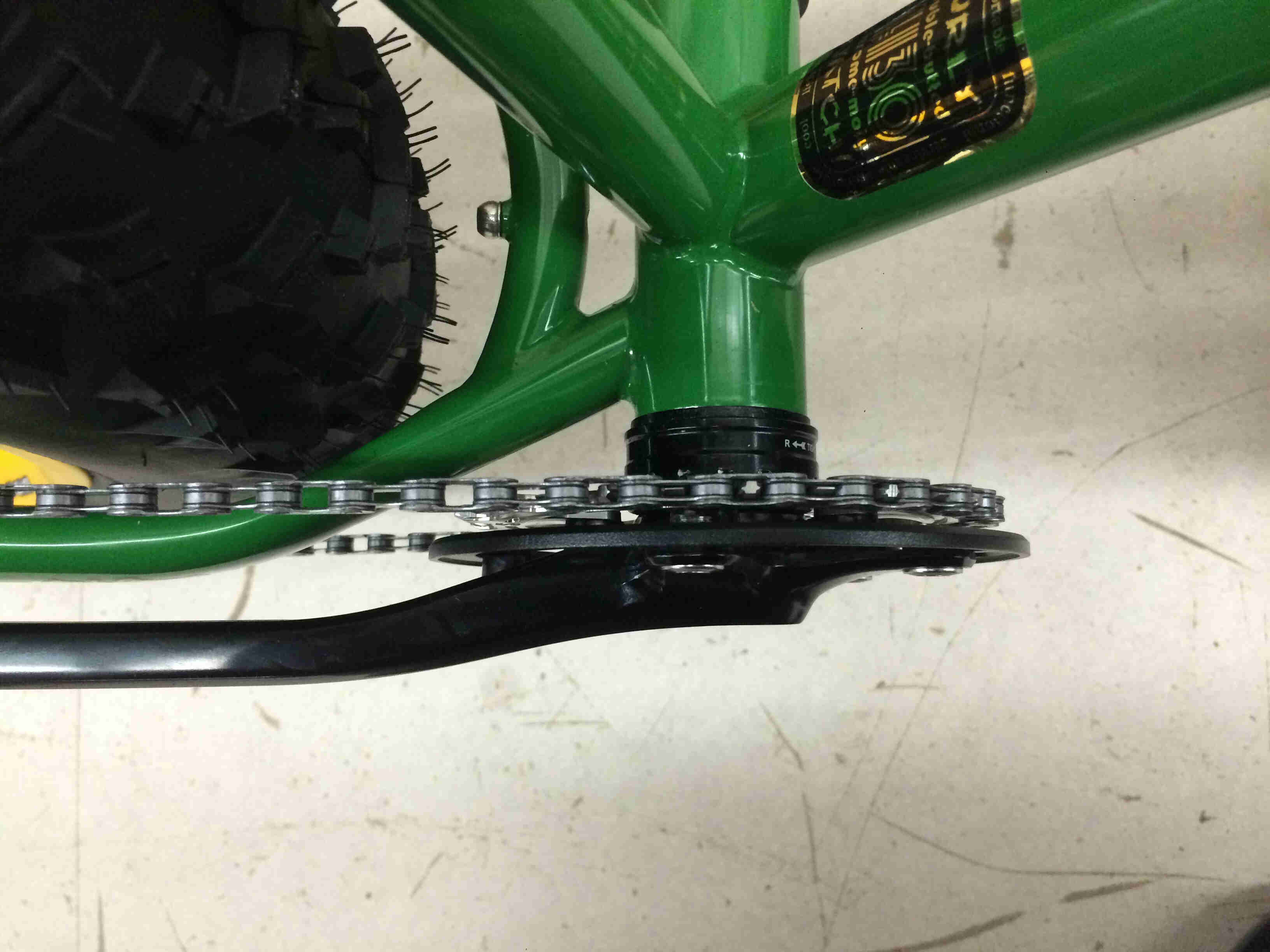 Close up, downward view of the crank and chainring of a green Surly Moonlander bike