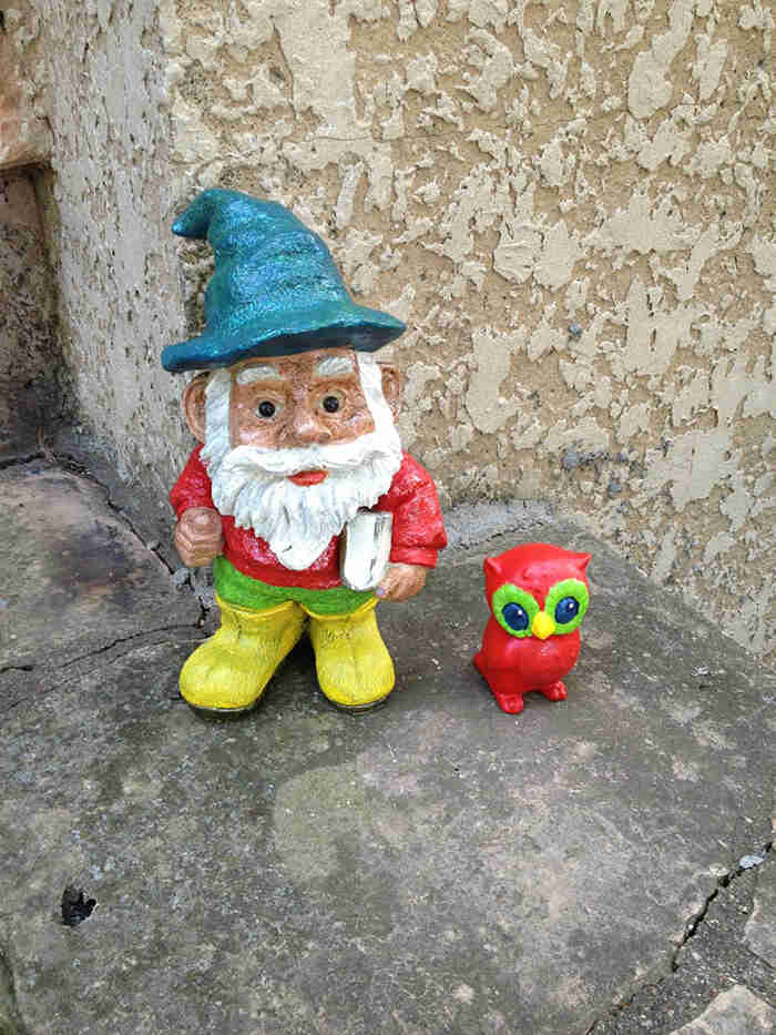Small painted troll and owl figurines, set on cement