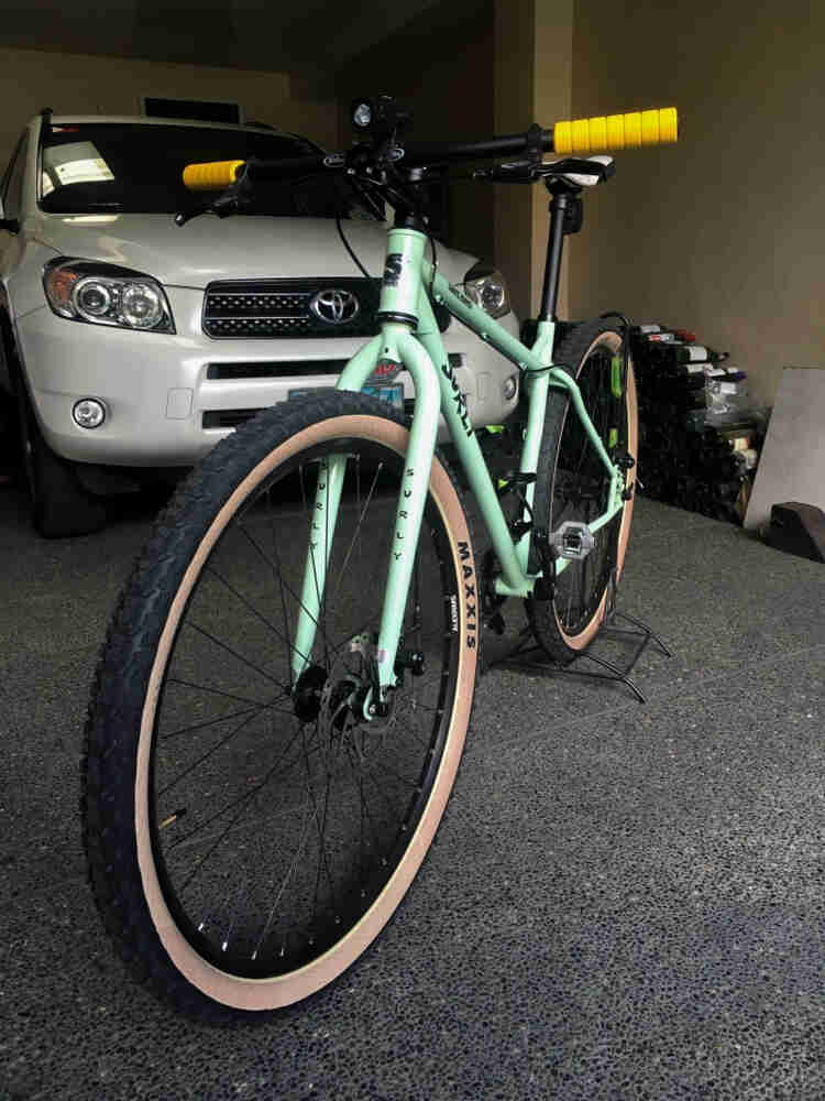 Front left side view of a mint Surly bike, parked inside a garage in front of an SUV