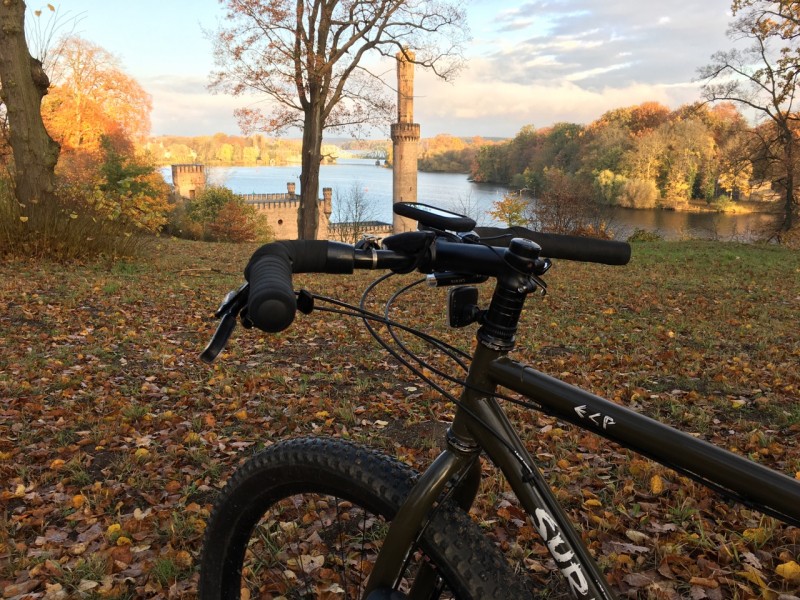 Cropped left side view of the front end of a Surly ECR bike in a field, with a castle and a river in the background