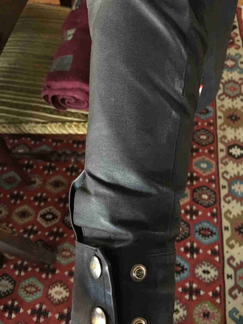 Downward view of the arm of a Surly V1 jacket, above a rug on the floorA